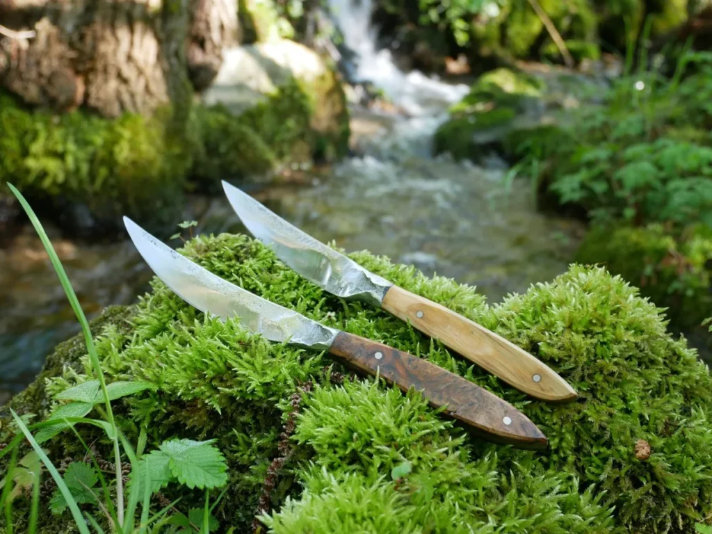 Deux couteaux le furieux posé sur de la mousse avec ruisseau en fond